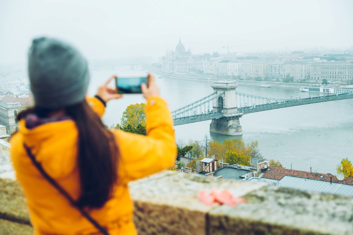 a girl clicking picture of a bridge in Budapest
