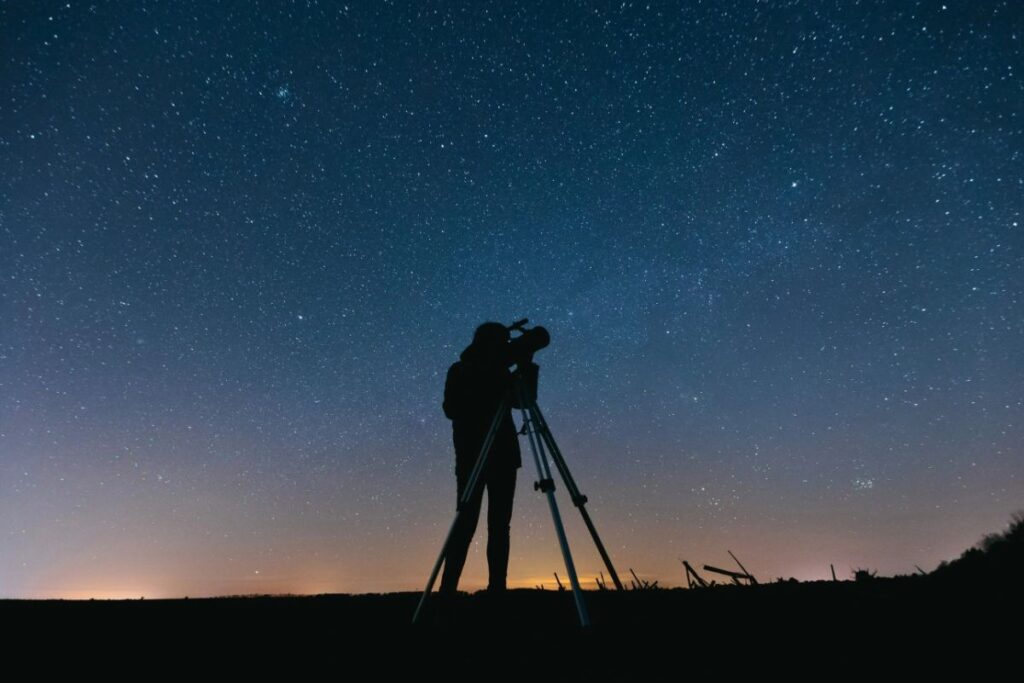 a person doing astrophotography in night using a telescope