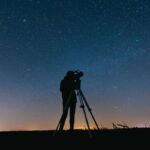 a person doing astrophotography in night using a telescope