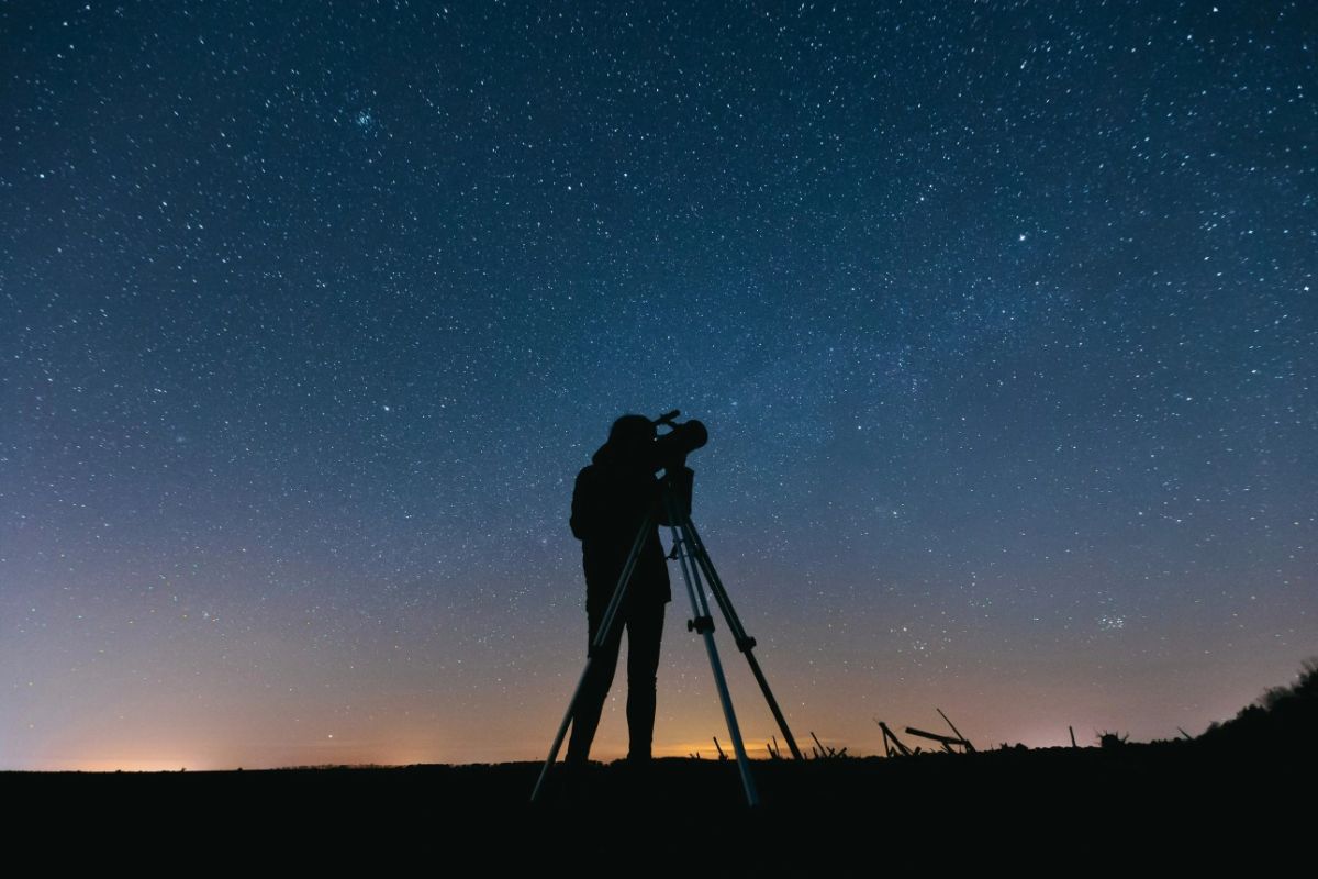a person doing astrophotography in night using a telescope